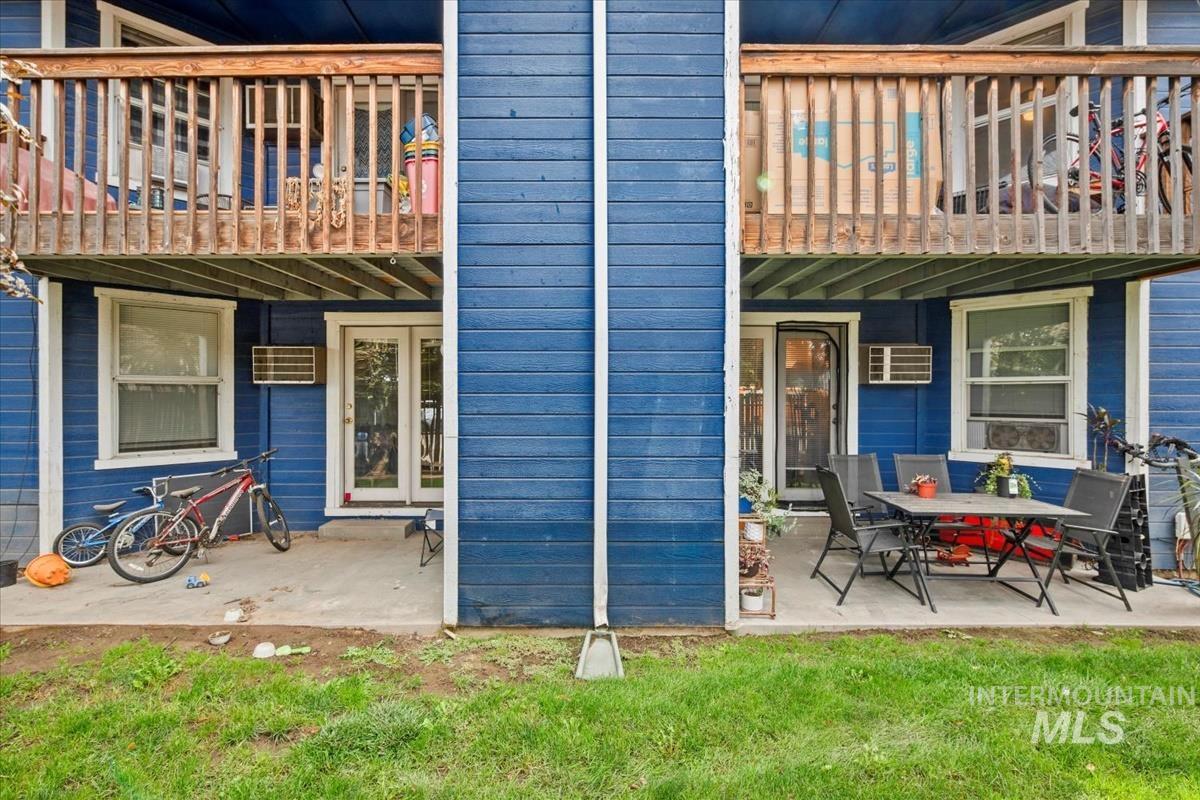 Back of house featuring a balcony, a patio area, a yard, and a wall unit AC