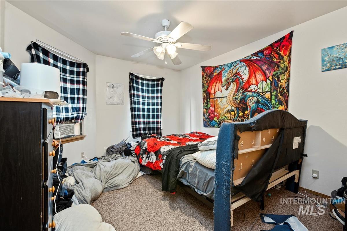 Carpeted bedroom with a ceiling fan and cooling unit