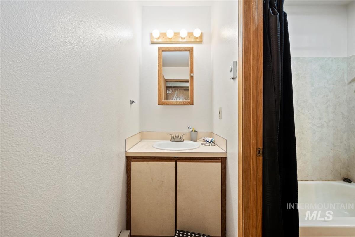 Bathroom with a bath, vanity, and a textured wall