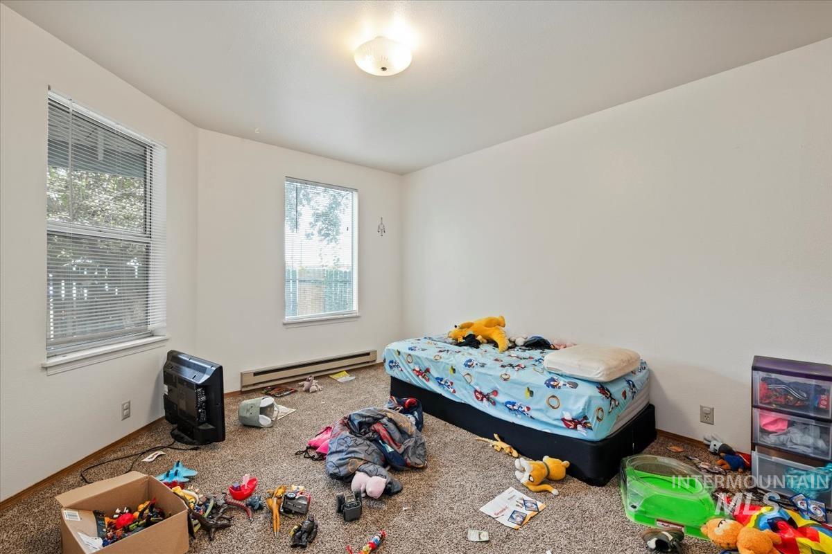 Carpeted bedroom featuring a baseboard radiator