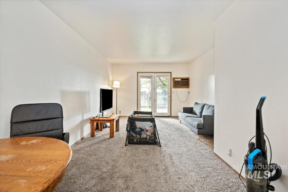 Living area featuring carpet and a wall mounted air conditioner