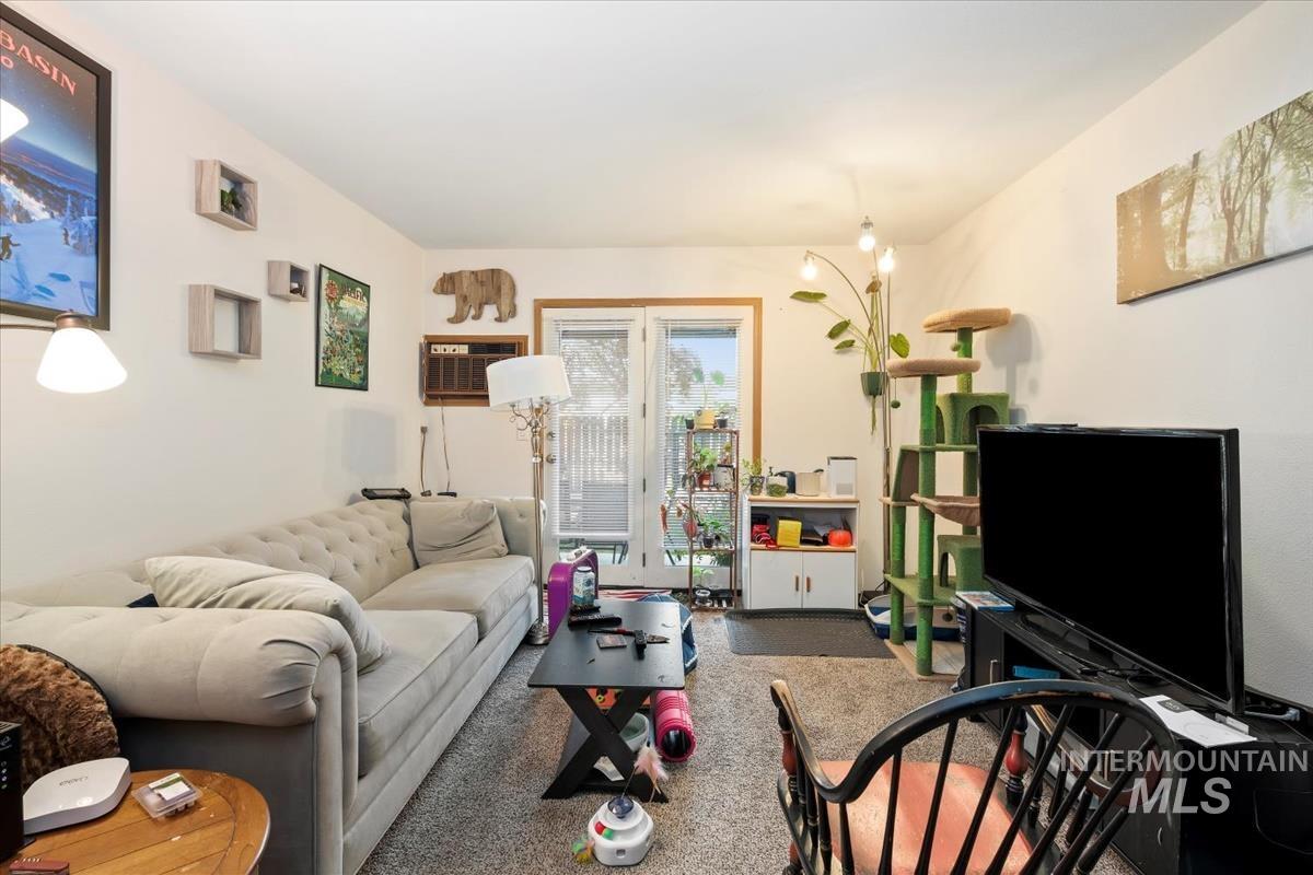 Living area featuring carpet flooring and a wall unit AC