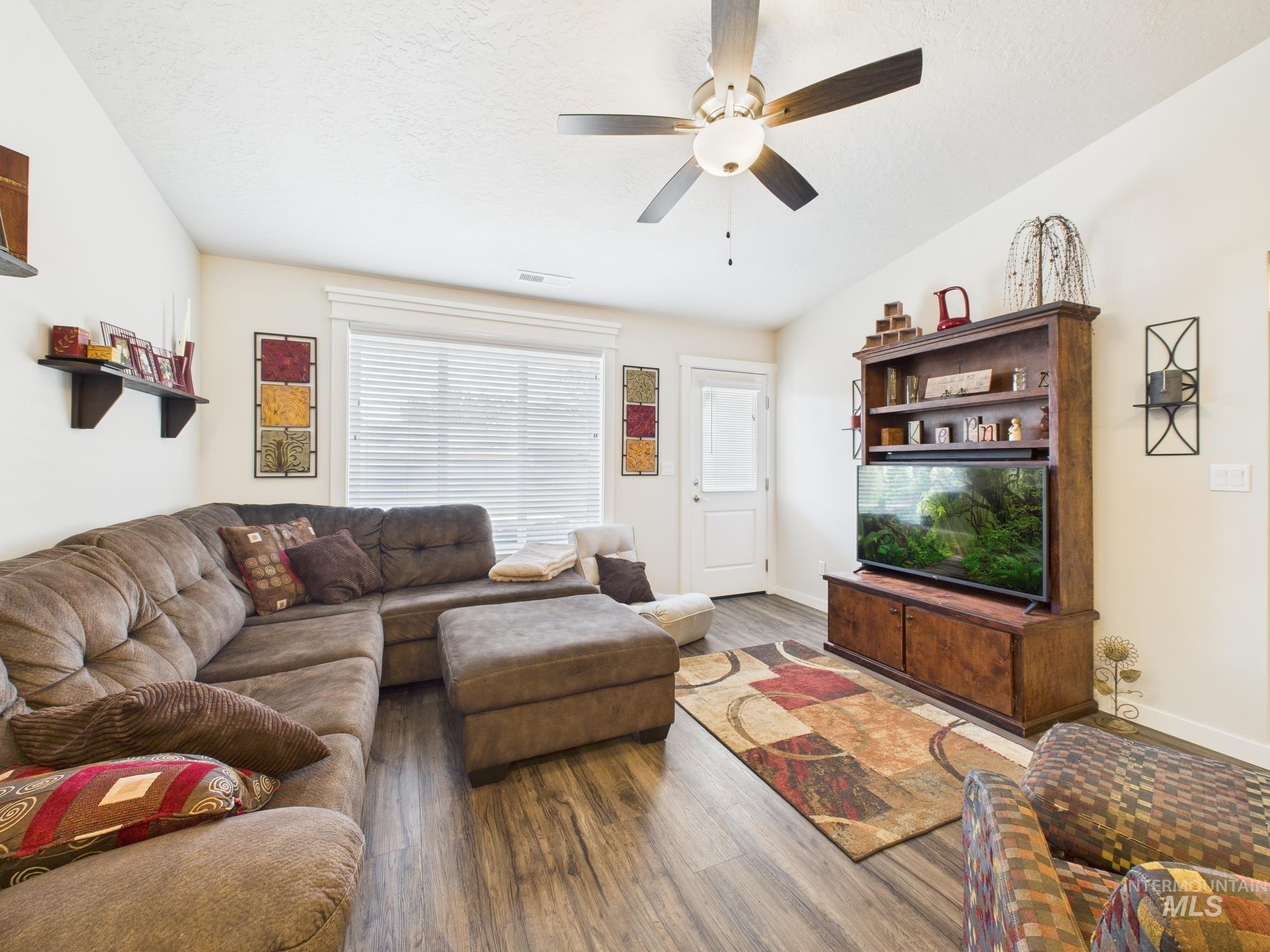 Living room with wood finished floors, ceiling fan, and a textured ceiling