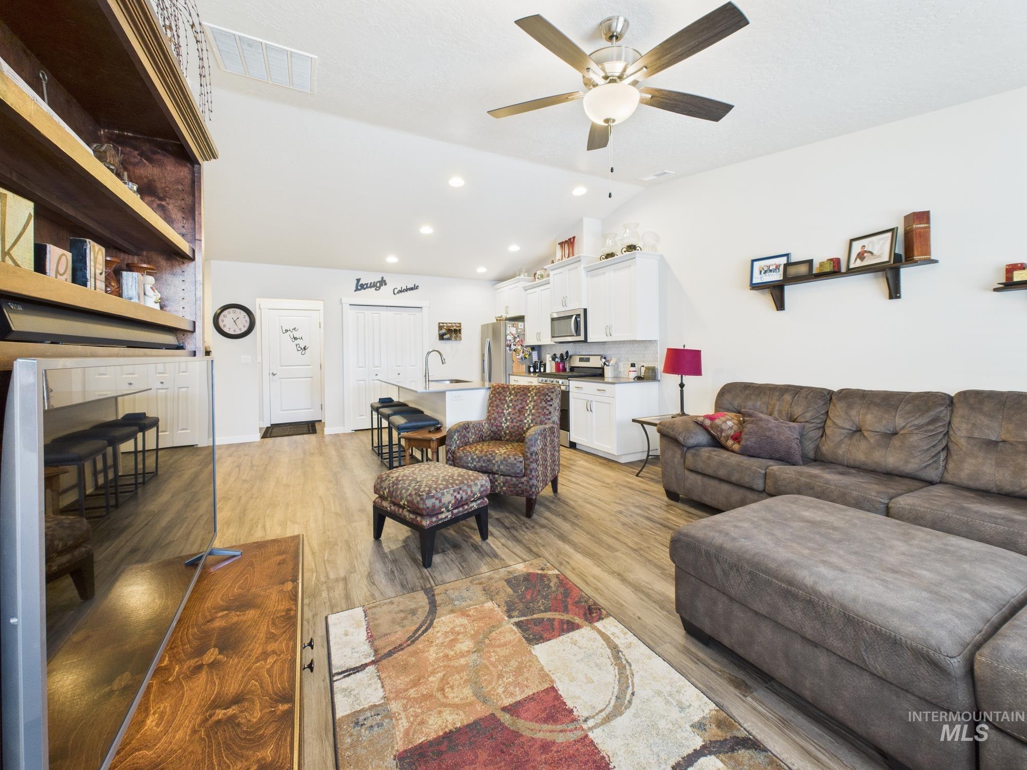 Living room featuring light wood-style floors, vaulted ceiling, recessed lighting, and ceiling fan