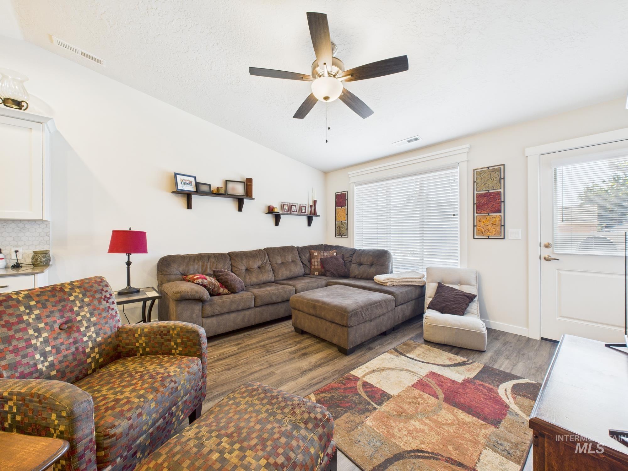 Living room featuring plenty of natural light, wood finished floors, ceiling fan, and a textured ceiling