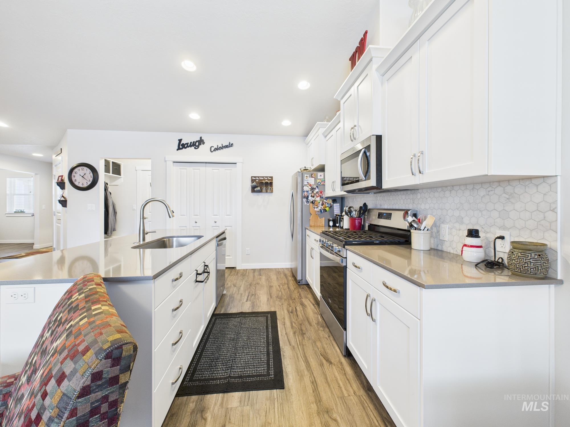 Kitchen with white cabinets, appliances with stainless steel finishes, decorative backsplash, an island with sink, and recessed lighting