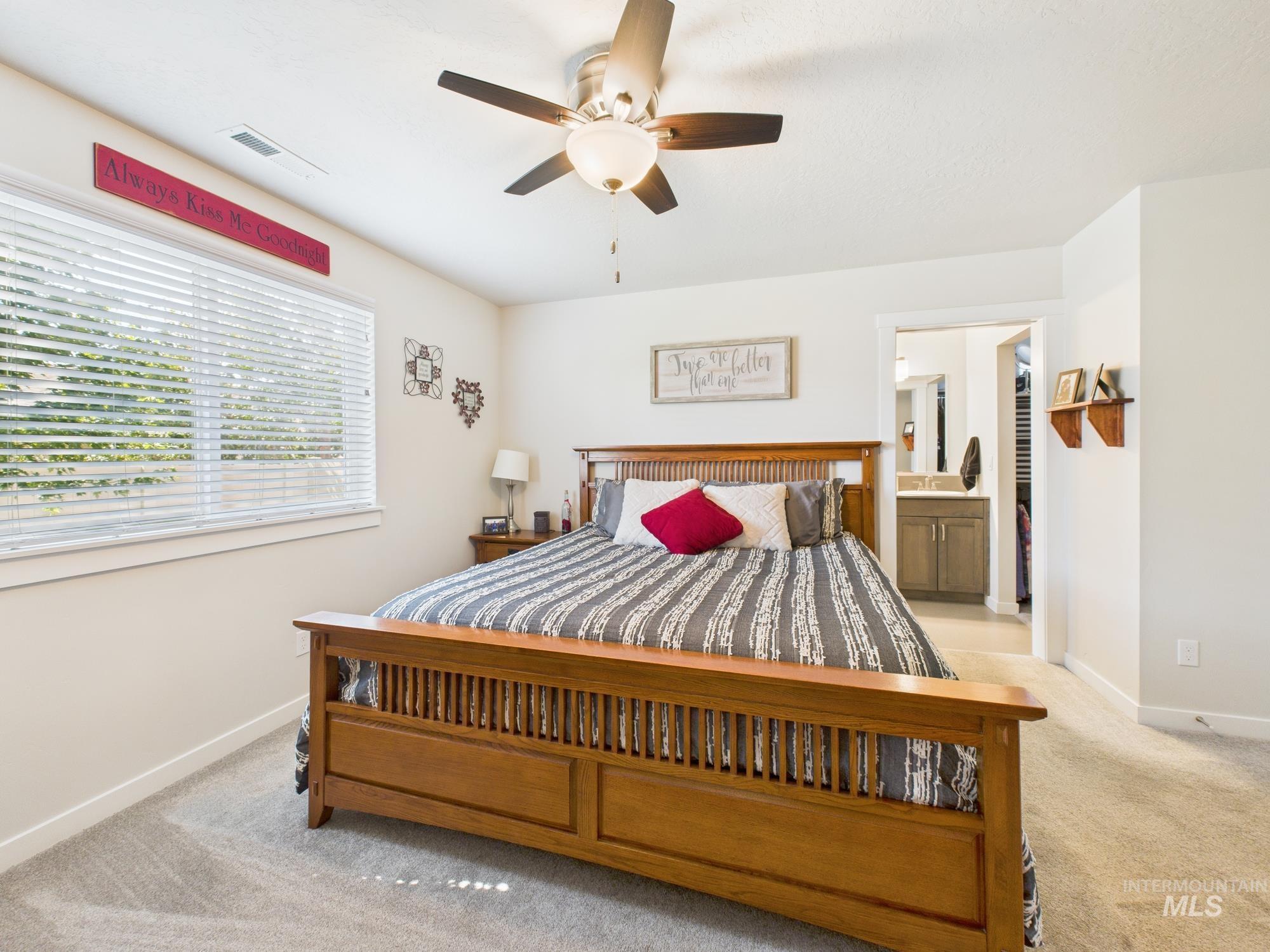 Carpeted bedroom featuring connected bathroom and ceiling fan