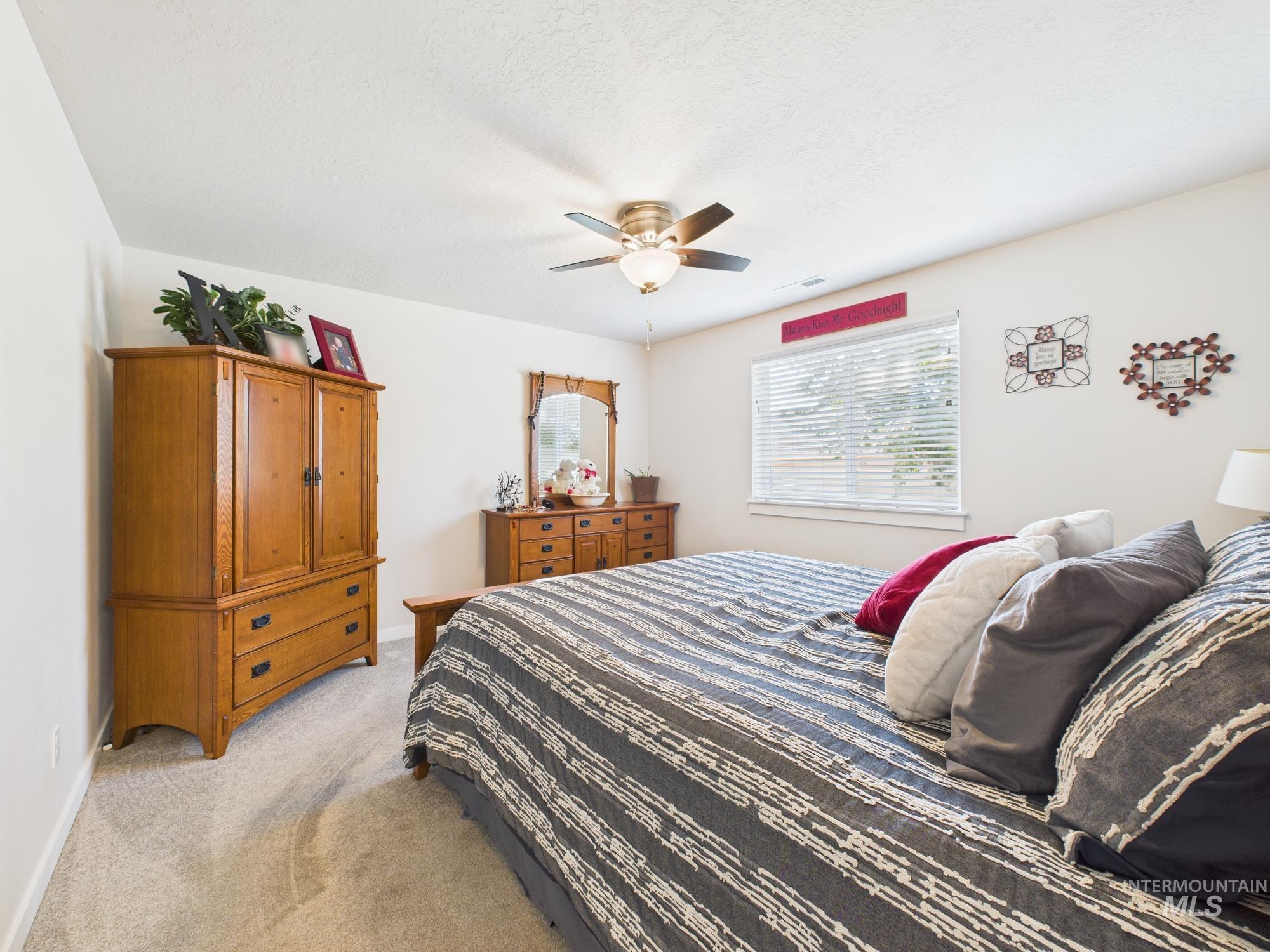 Carpeted bedroom with a ceiling fan and a textured ceiling