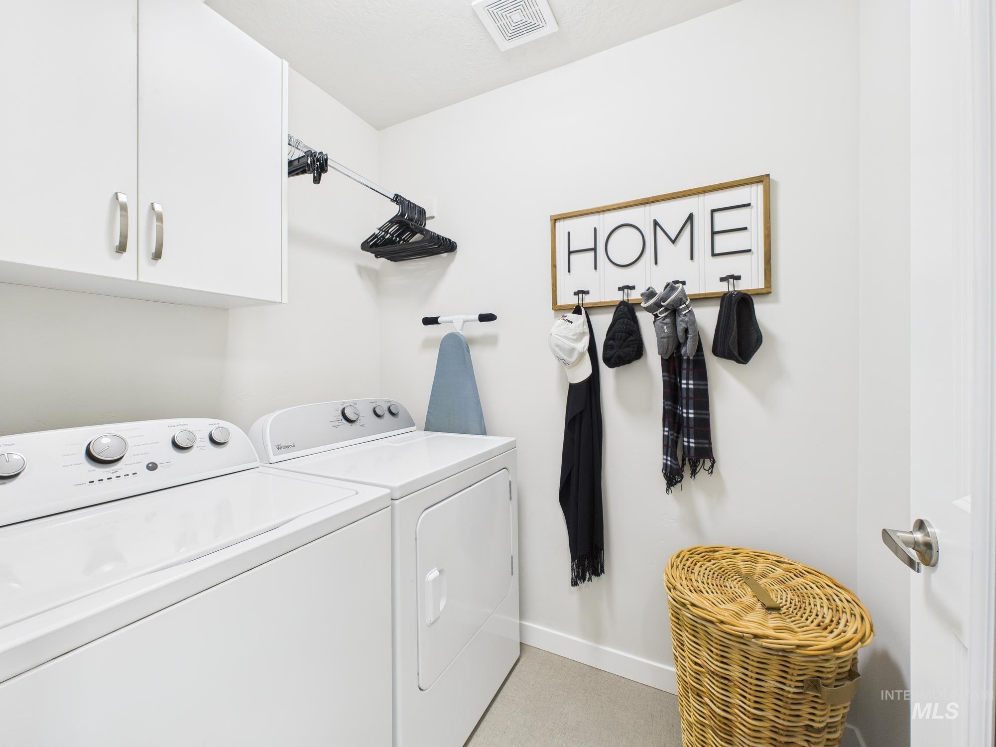 Laundry area featuring independent washer and dryer and cabinet space