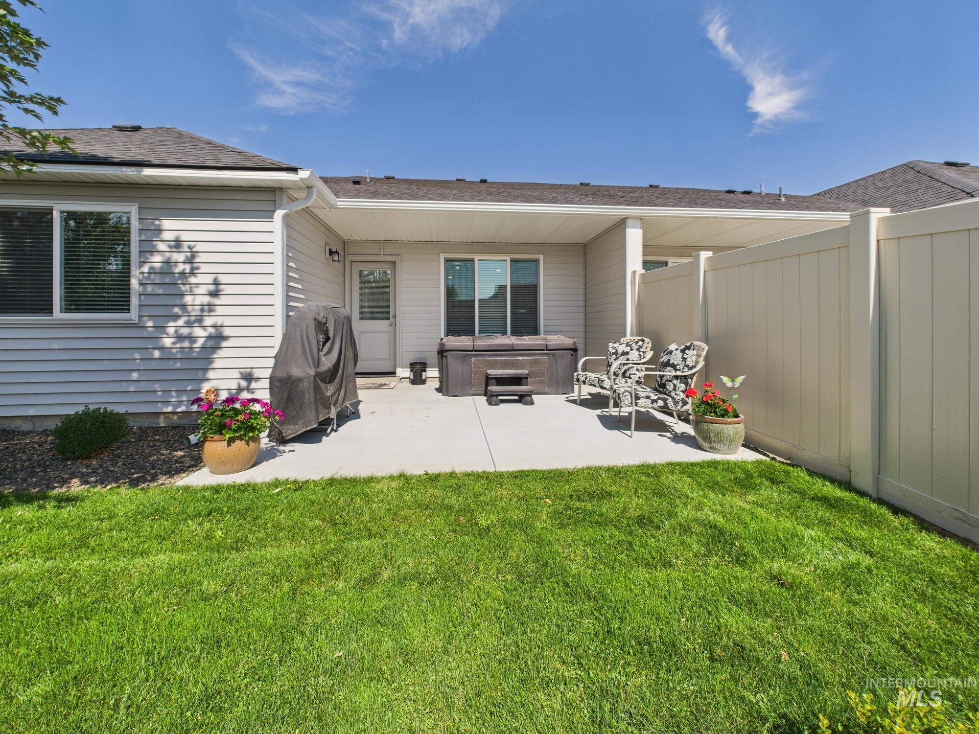 Rear view of property with a hot tub, a patio area, and a shingled roof