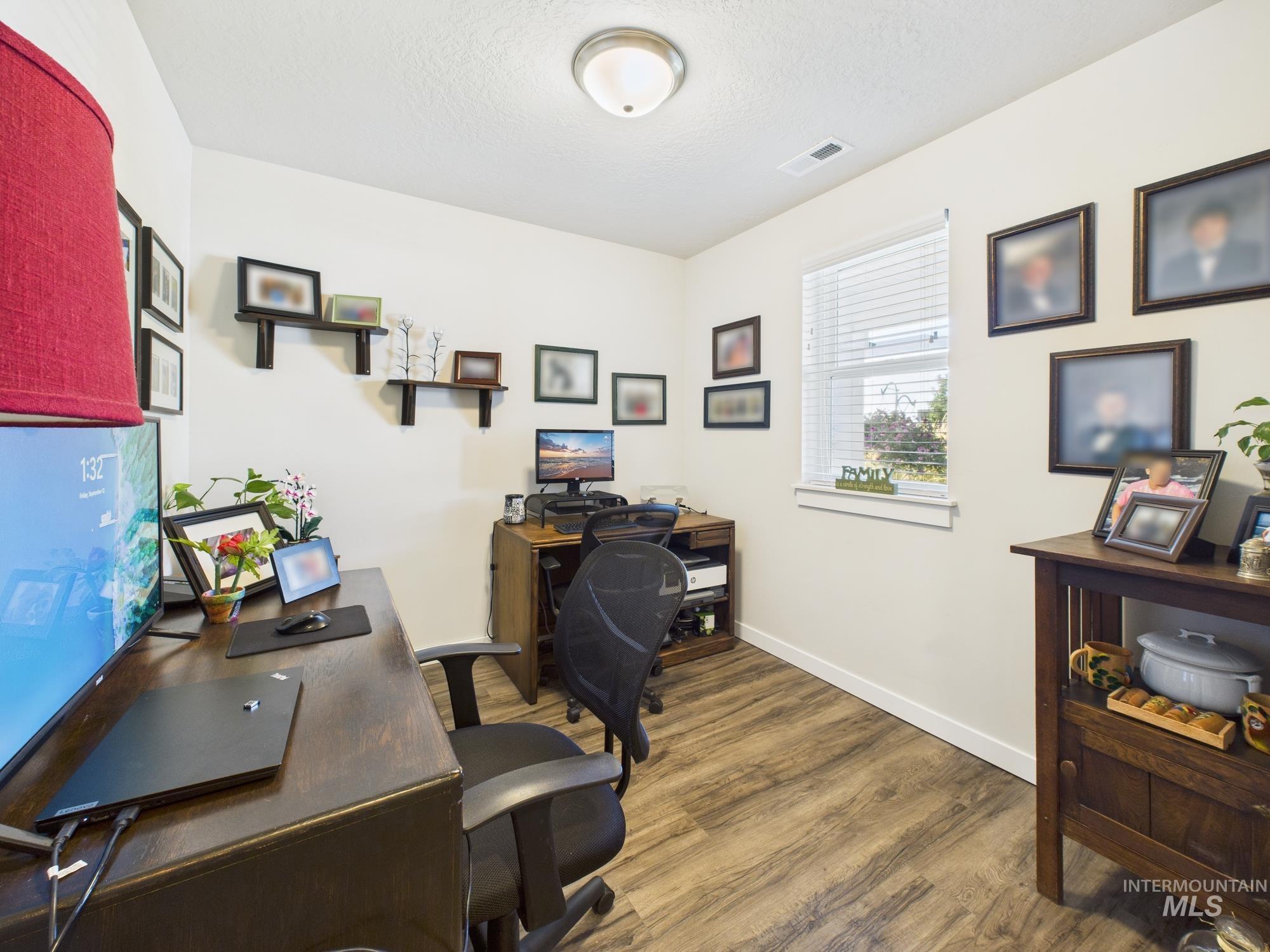 Home office with wood finished floors and a textured ceiling