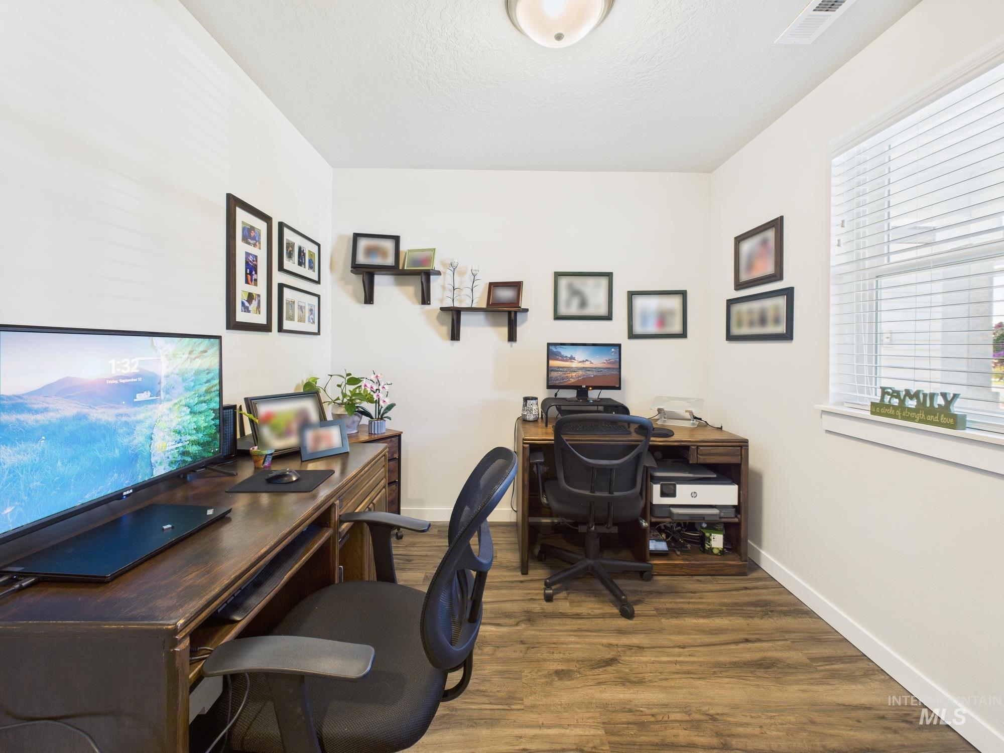Home office with dark wood-style floors and a textured ceiling
