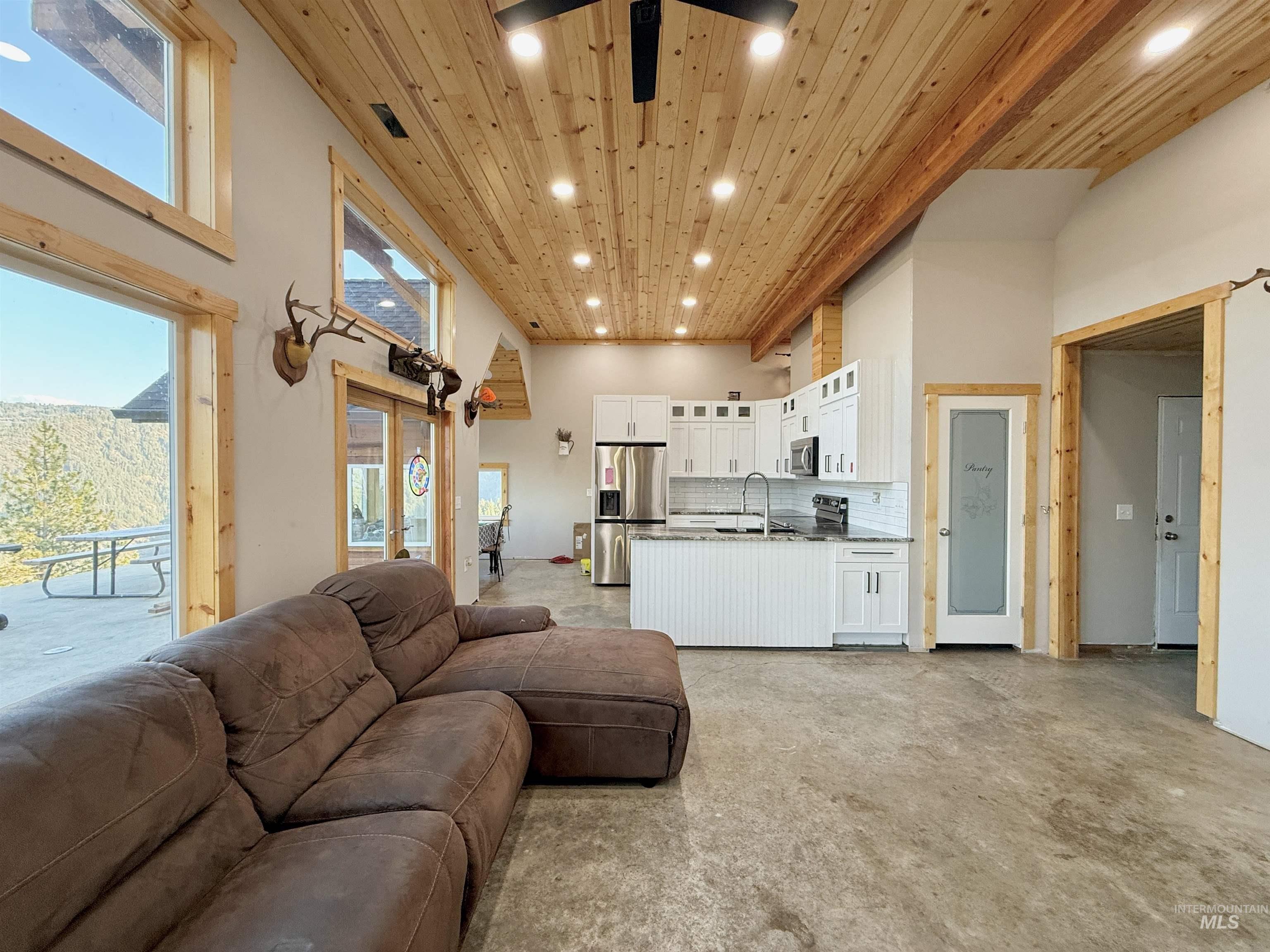 Living room featuring wooden ceiling, recessed lighting, a high ceiling, and concrete floors