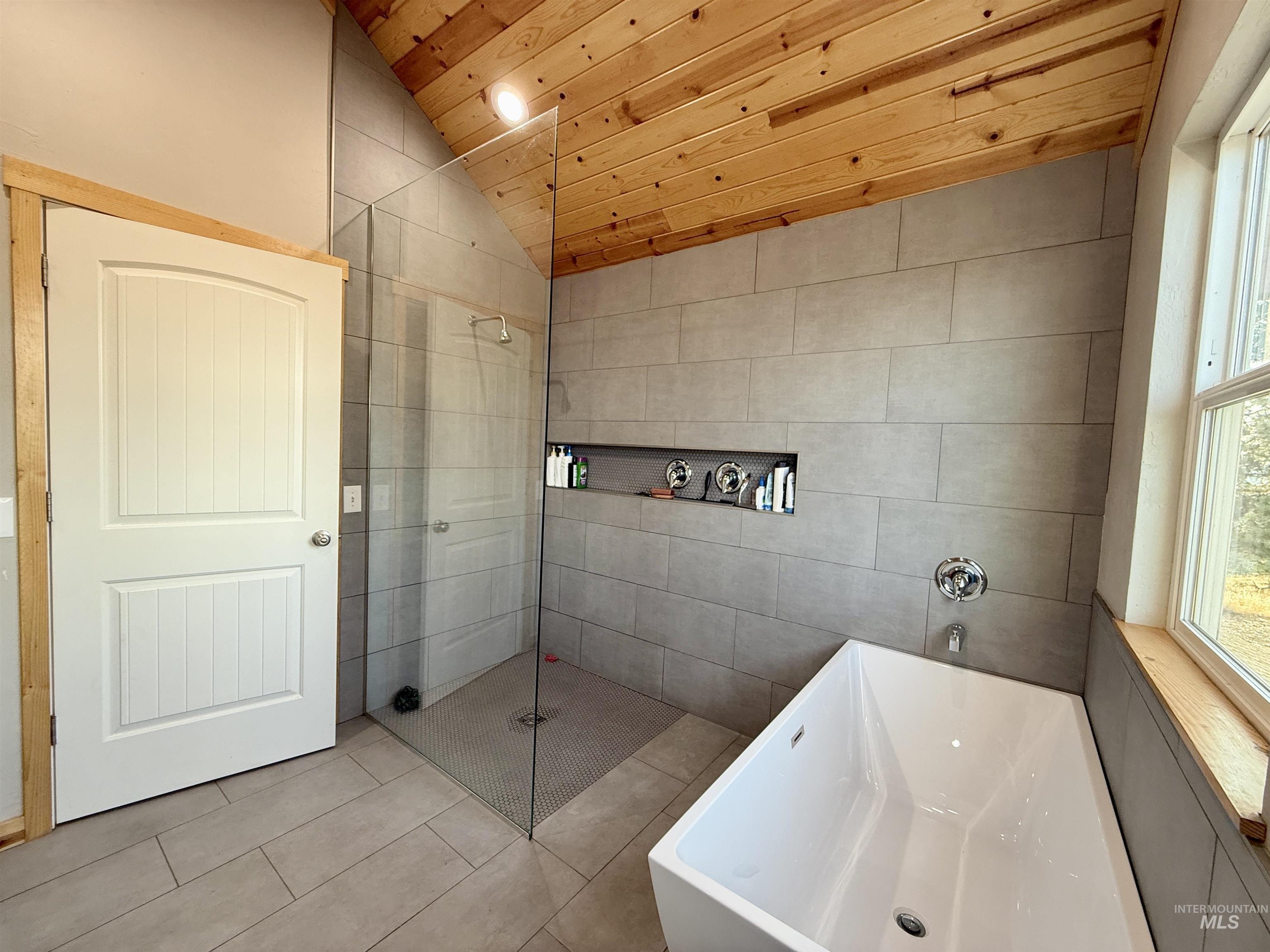 Full bathroom with wooden ceiling, lofted ceiling, a freestanding bath, tile patterned flooring, and a stall shower
