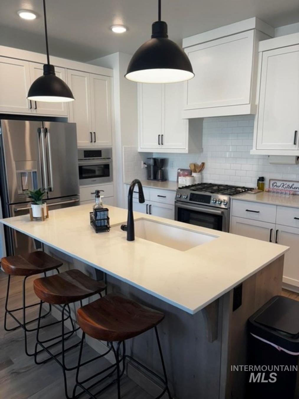 Kitchen with white cabinetry, backsplash, stainless steel appliances, a breakfast bar, and recessed lighting