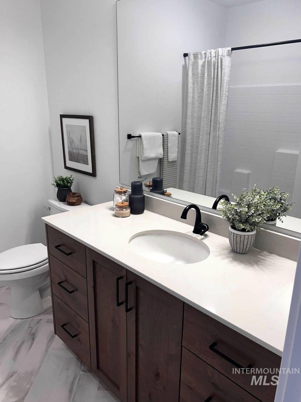 Full bathroom with vanity, curtained shower, and light marble finish floors