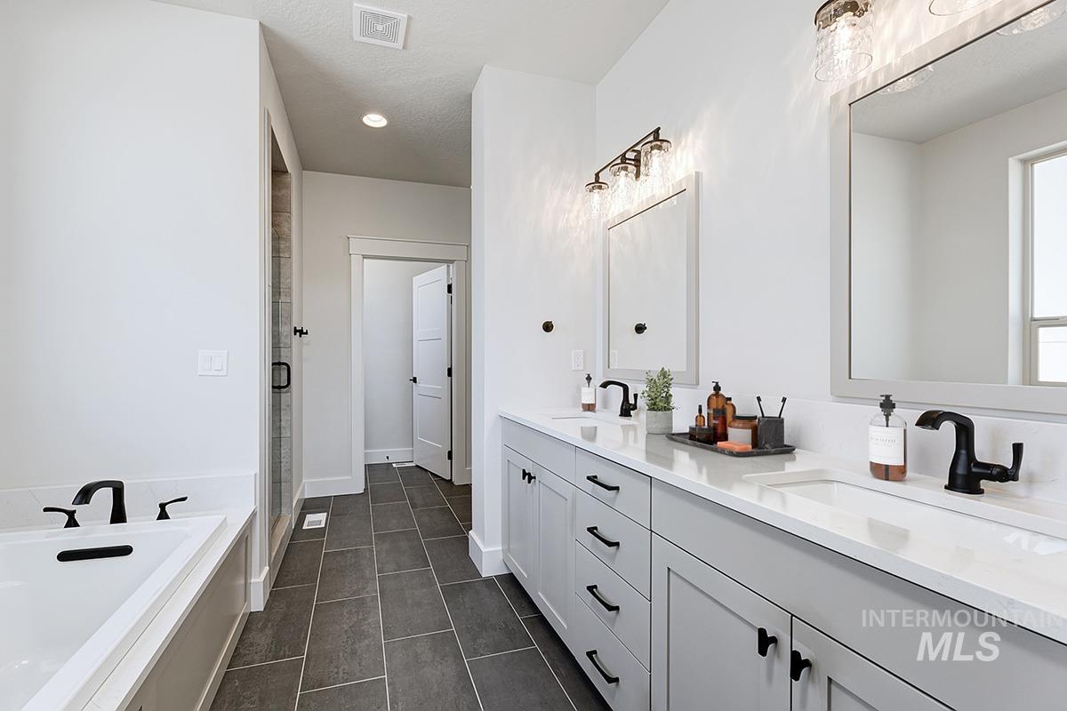 Bathroom with double vanity, a garden tub, a shower stall, dark tile patterned flooring, and a textured ceiling