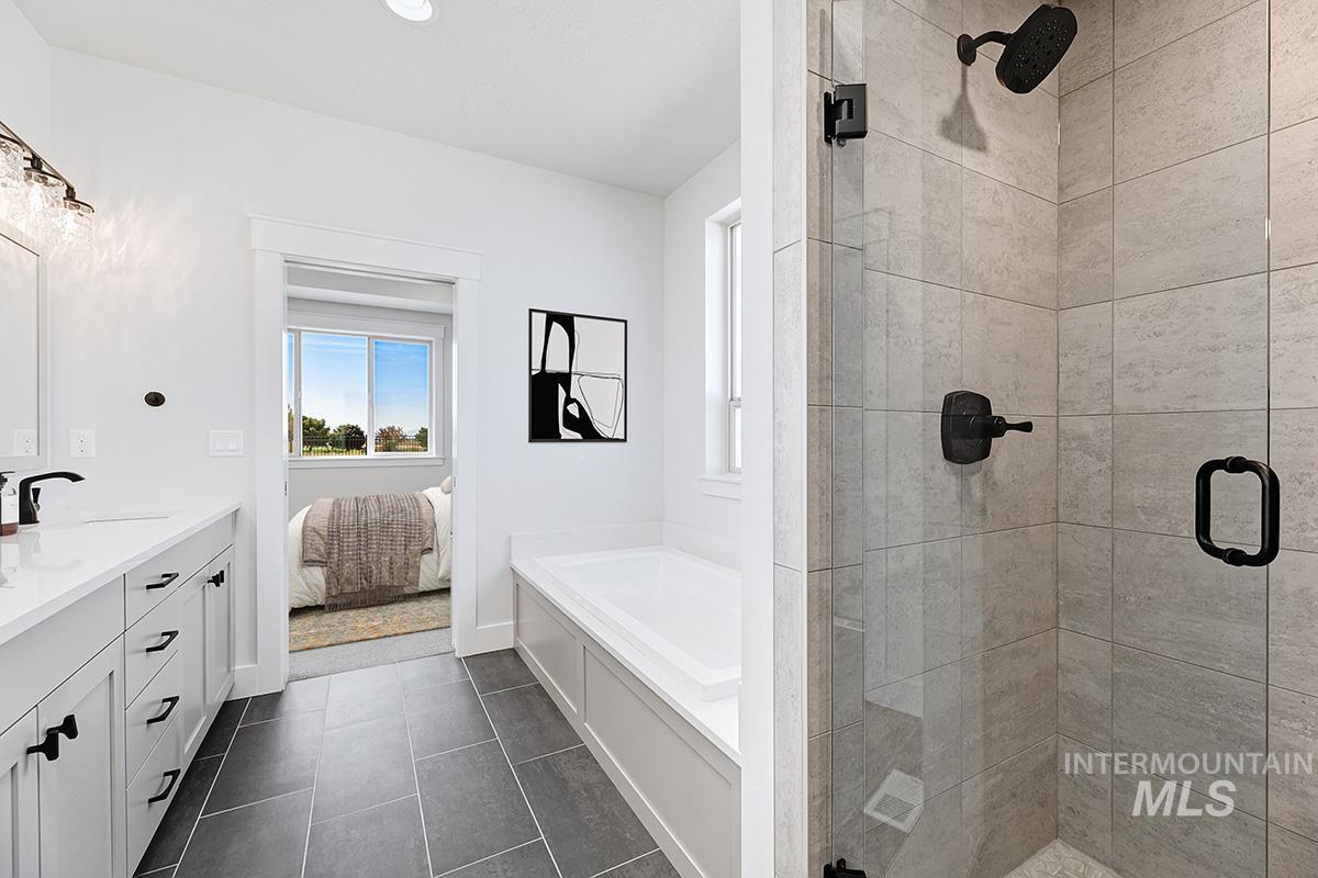 Bathroom with a stall shower, a bath, double vanity, dark tile patterned floors, and ensuite bathroom