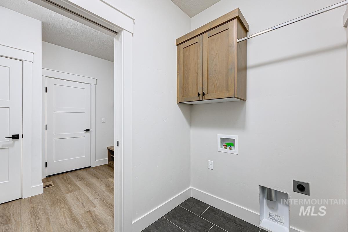Washroom featuring hookup for a washing machine, hookup for an electric dryer, cabinet space, a textured ceiling, and dark wood finished floors