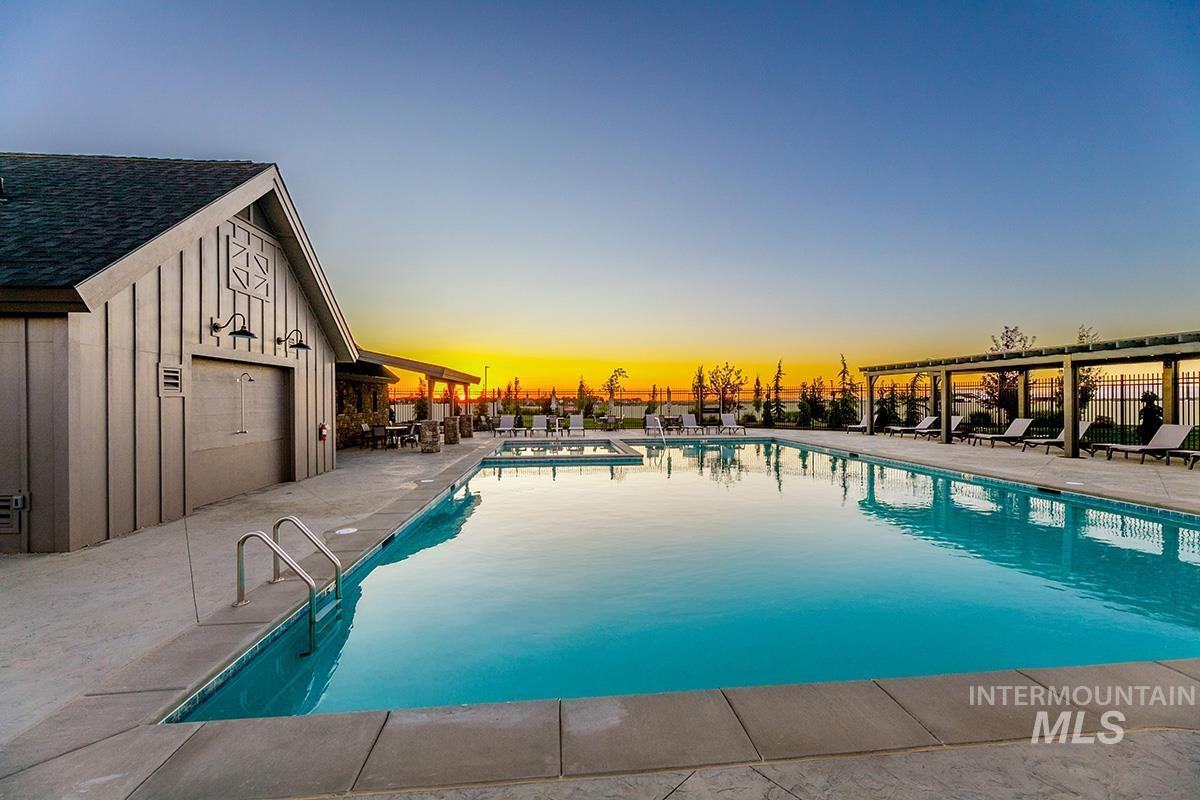 Pool at dusk featuring a patio area and a community pool
