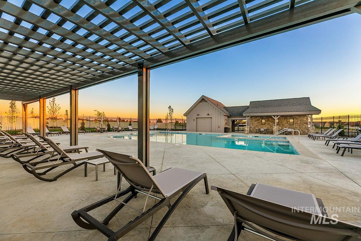 Pool at dusk with a community pool, a patio, and a pergola