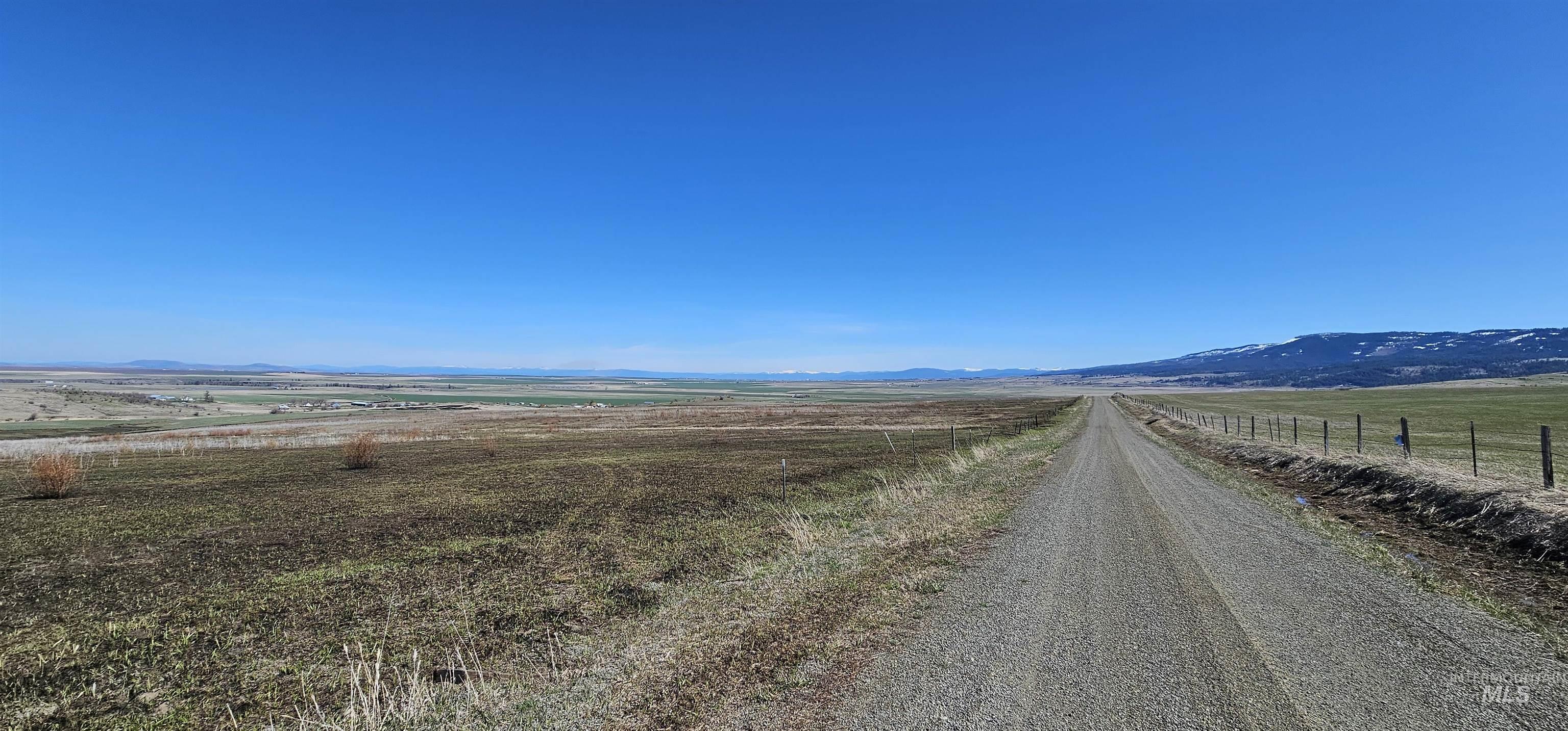 View of dirt / gravel road featuring a view of rural / pastoral area and a mountain view