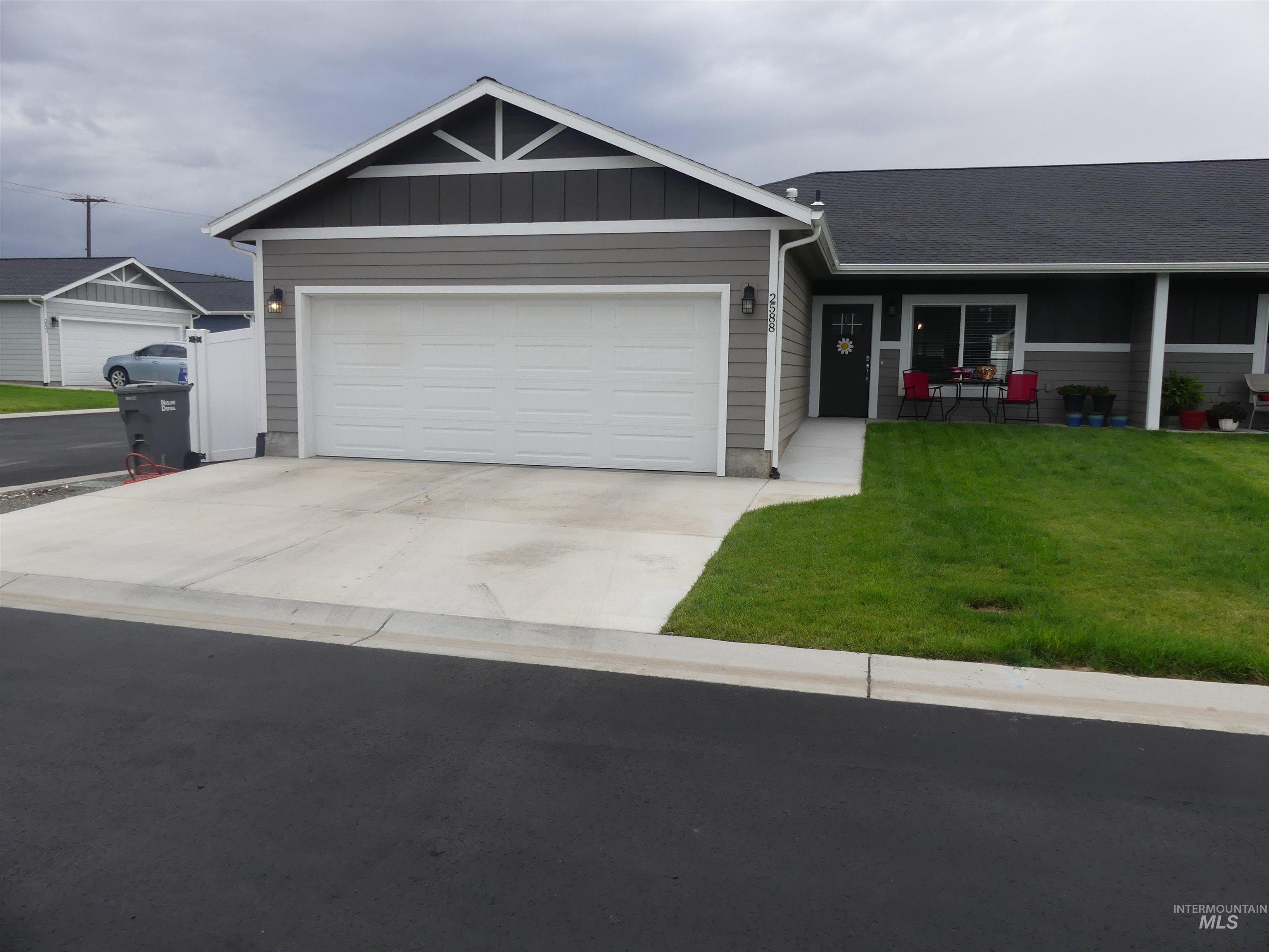 Ranch-style house featuring board and batten siding, a front lawn, driveway, and an attached garage