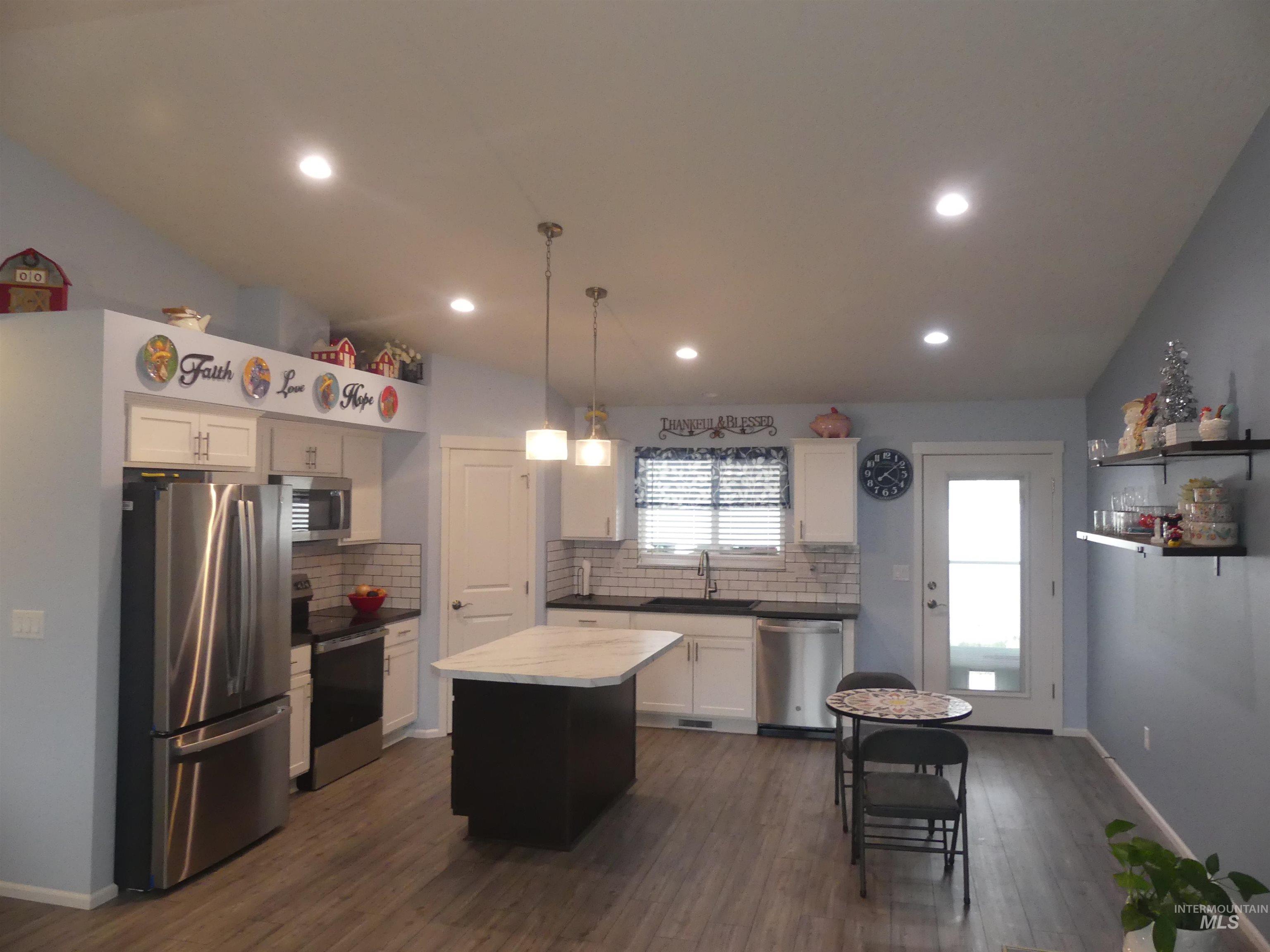 Kitchen featuring pendant lighting, appliances with stainless steel finishes, white cabinetry, backsplash, and recessed lighting