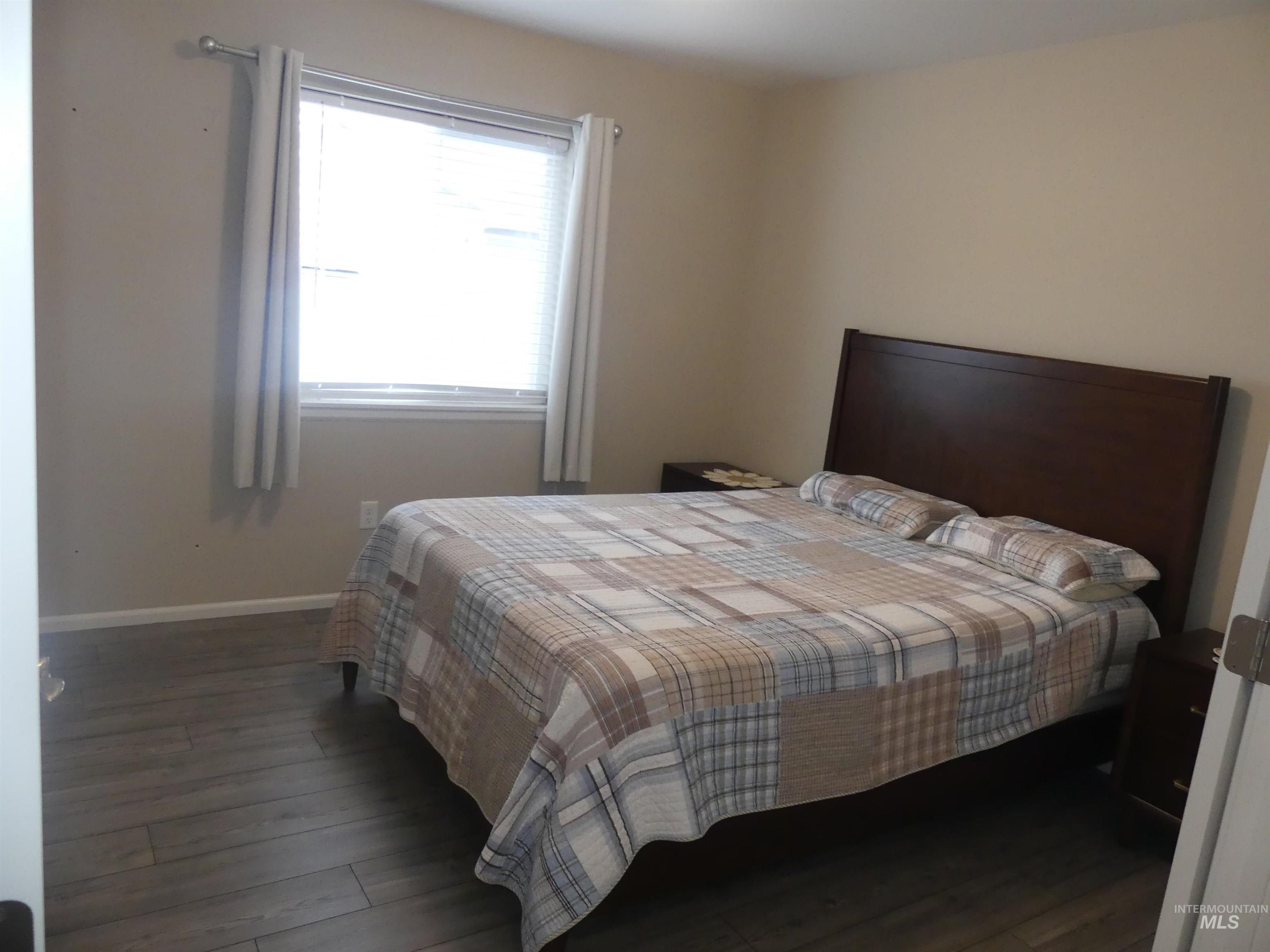 Bedroom with baseboards and dark wood-type flooring