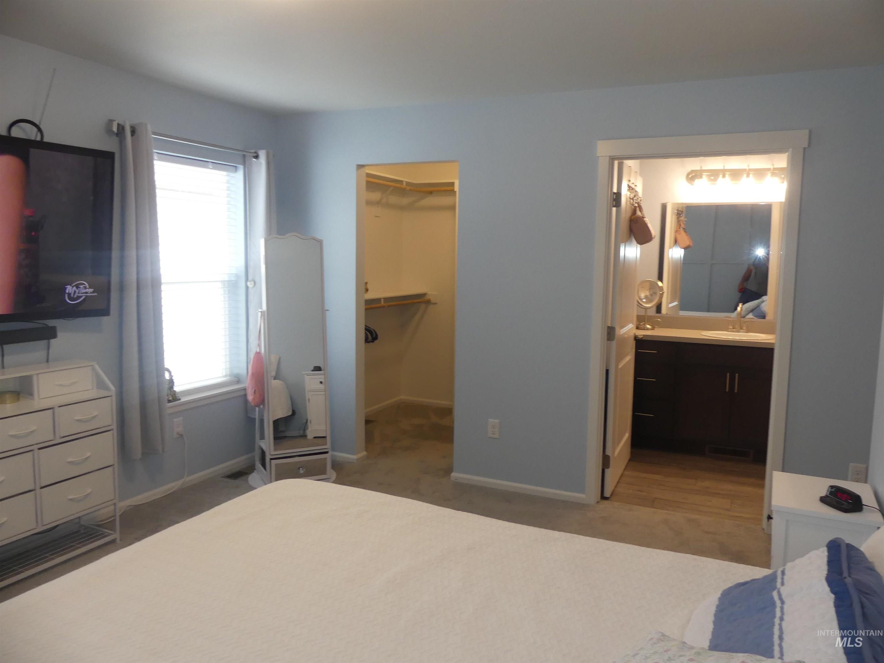 Bedroom featuring light colored carpet and a spacious closet