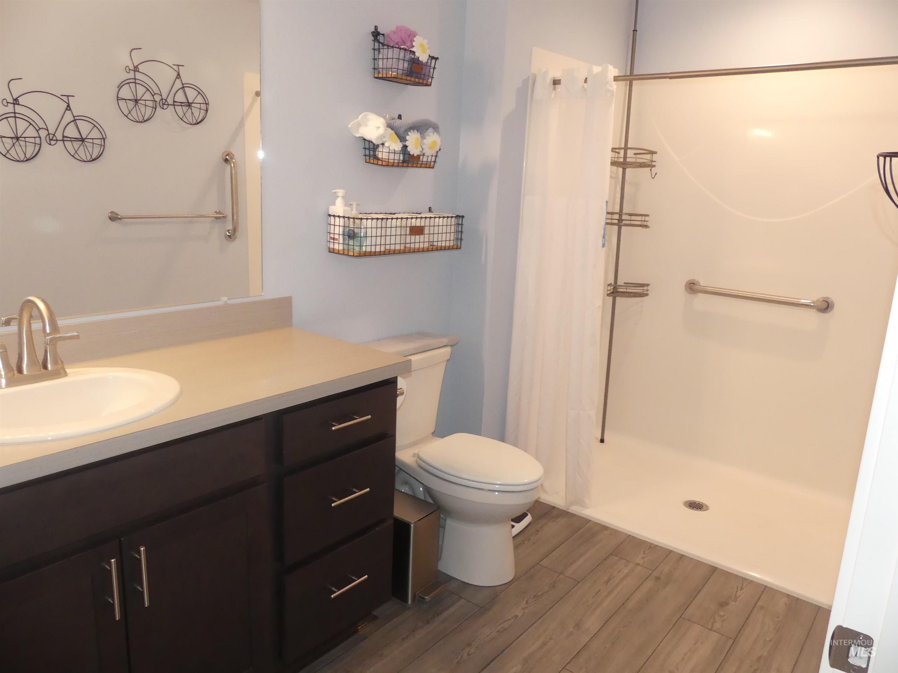 Full bath with vanity, a shower stall, and dark wood finished floors