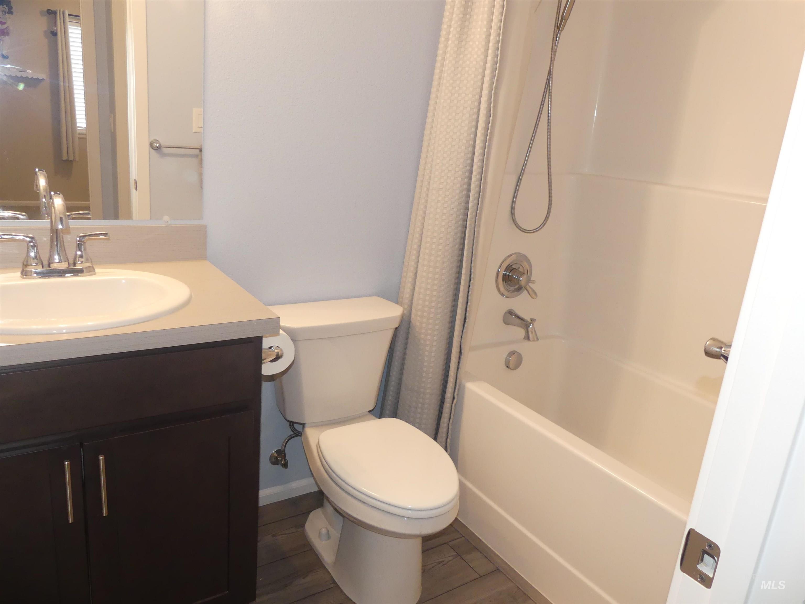 Bathroom featuring shower / bathtub combination with curtain, vanity, and wood finished floors