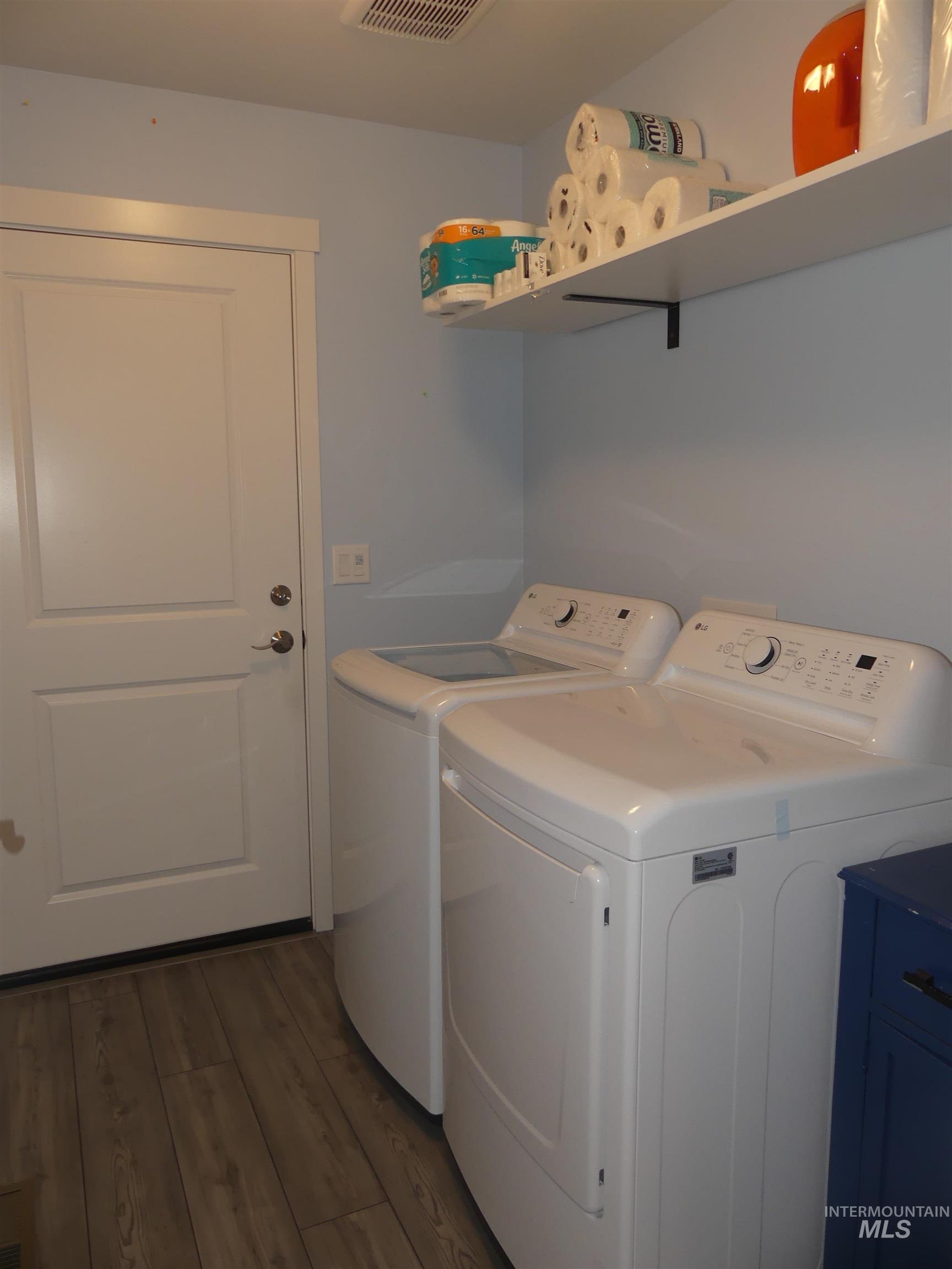 Laundry room with washing machine and clothes dryer and dark wood-style flooring