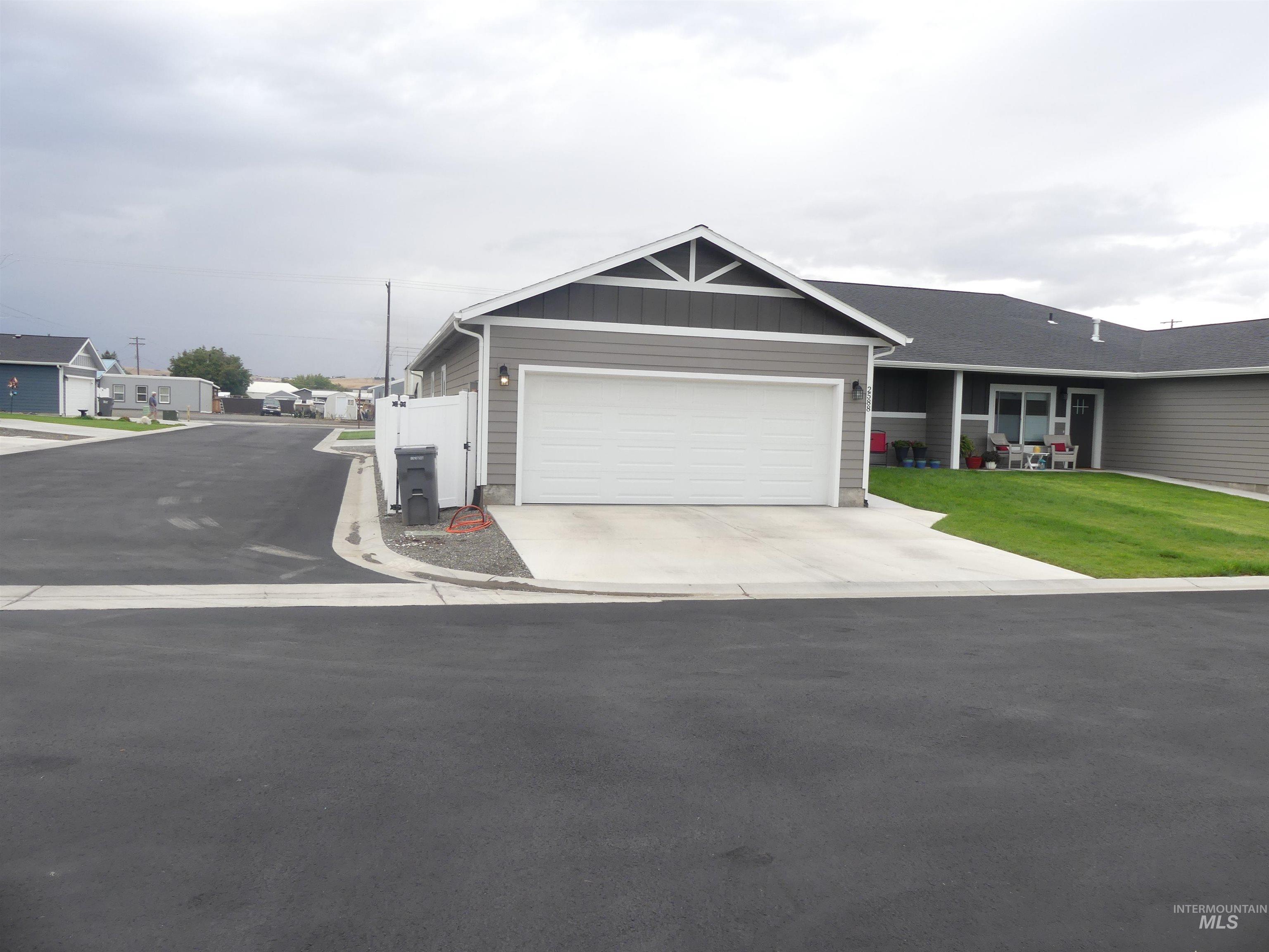 Single story home featuring board and batten siding, driveway, a garage, and a front lawn