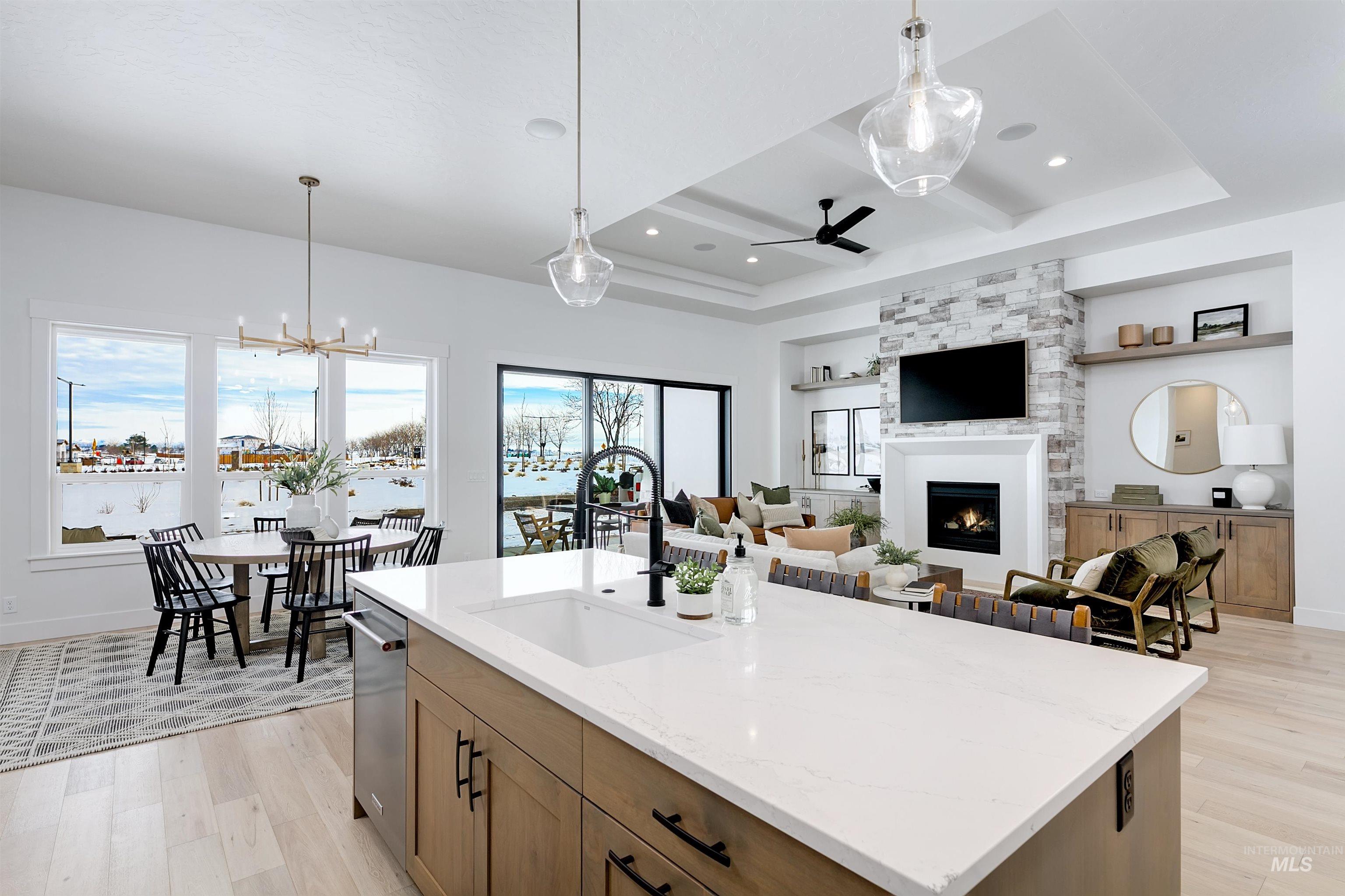 Kitchen with pendant lighting, light wood finished floors, light stone counters, an island with sink, and recessed lighting