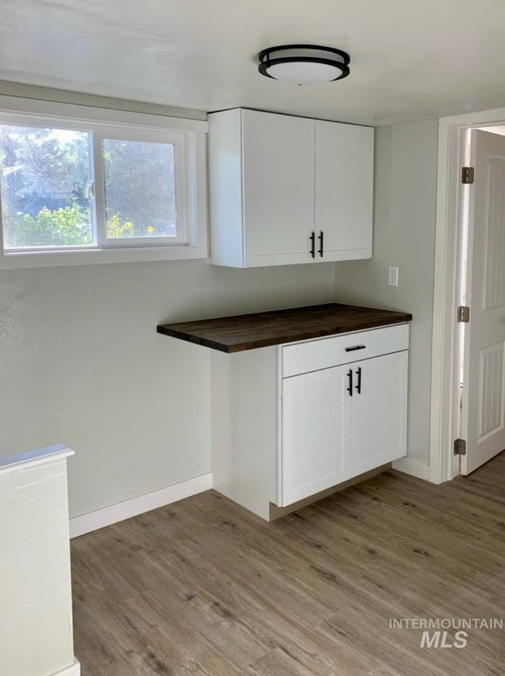 Kitchen with white cabinets, butcher block countertops, and light wood finished floors