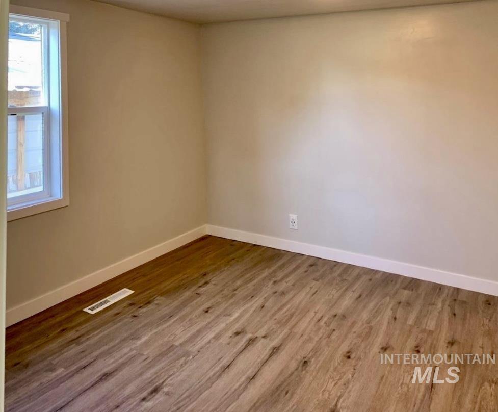 Spare room with baseboards and light wood-type flooring