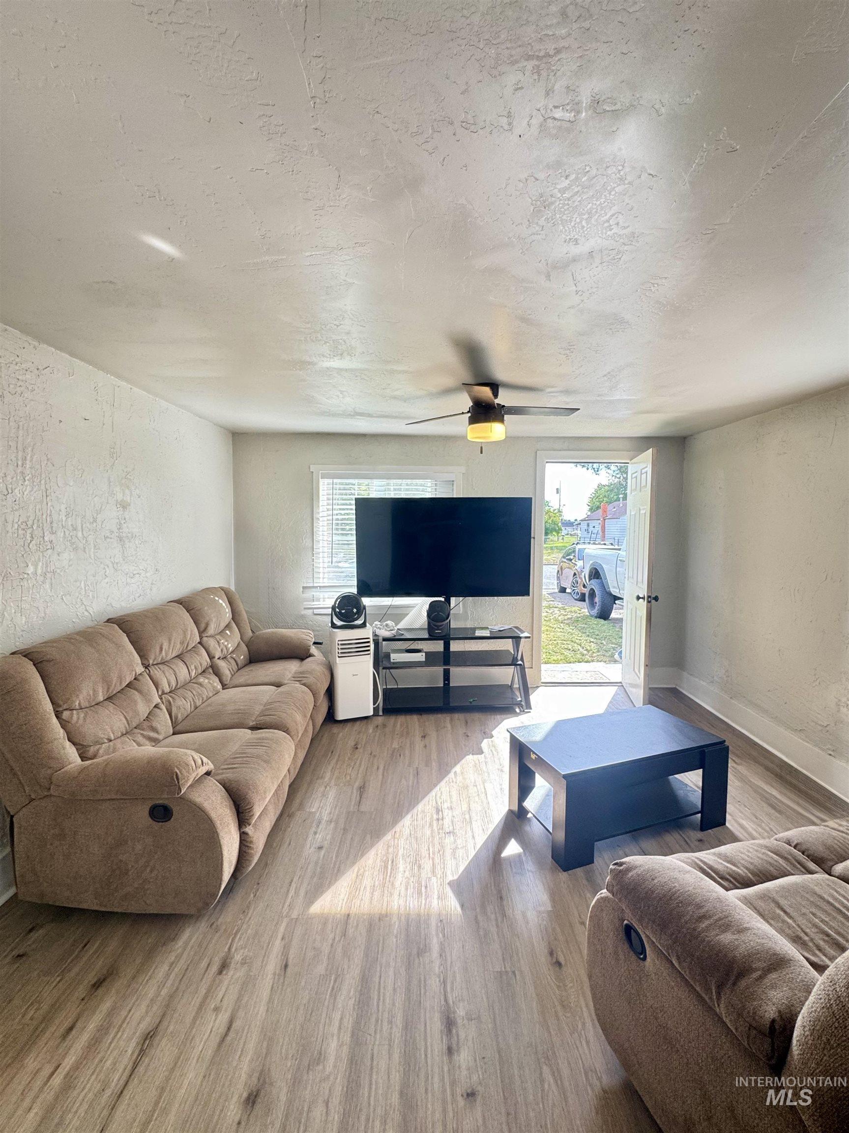 Living area featuring a textured wall, wood finished floors, a textured ceiling, and plenty of natural light