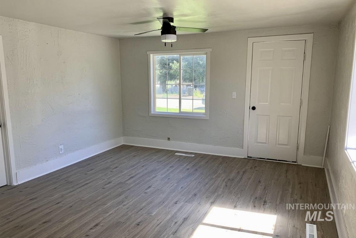 Spare room featuring a textured wall, wood finished floors, and a ceiling fan