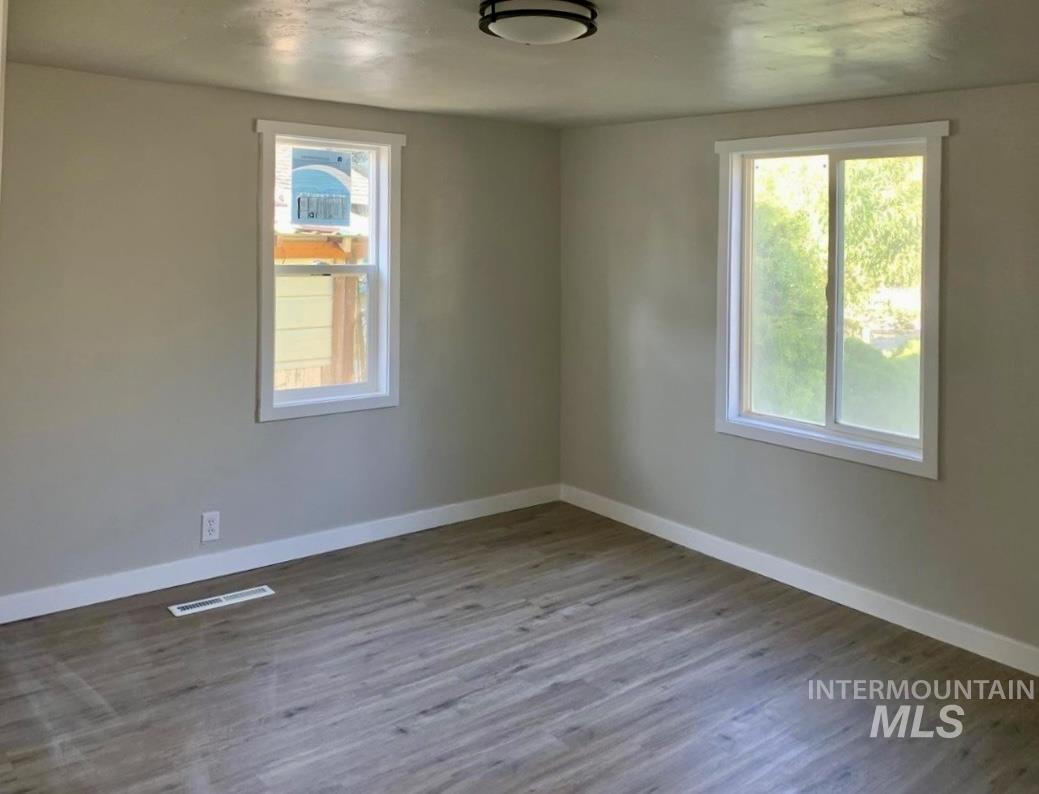 Empty room with dark wood-style flooring and healthy amount of natural light
