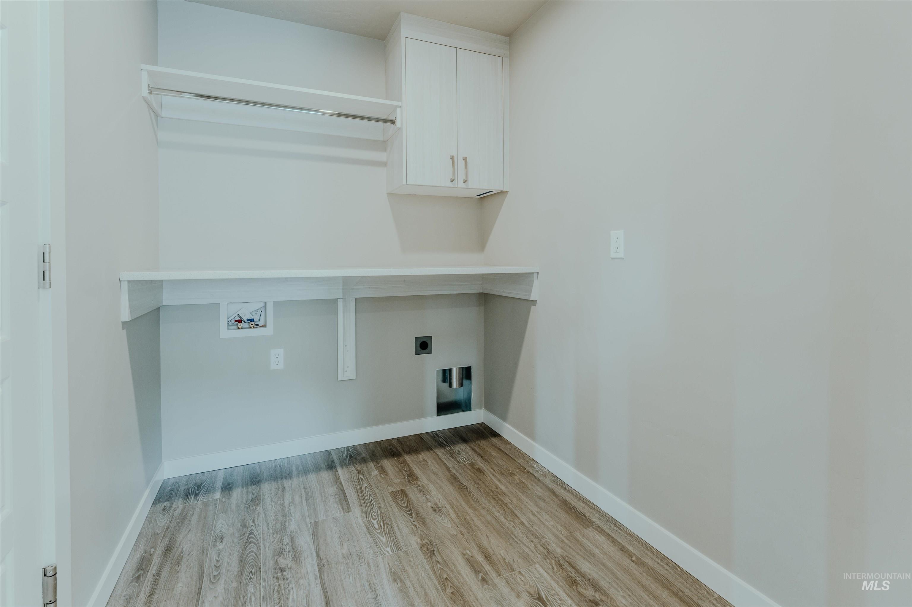 Laundry room featuring light wood-type flooring, hookup for an electric dryer, cabinet space, and hookup for a washing machine