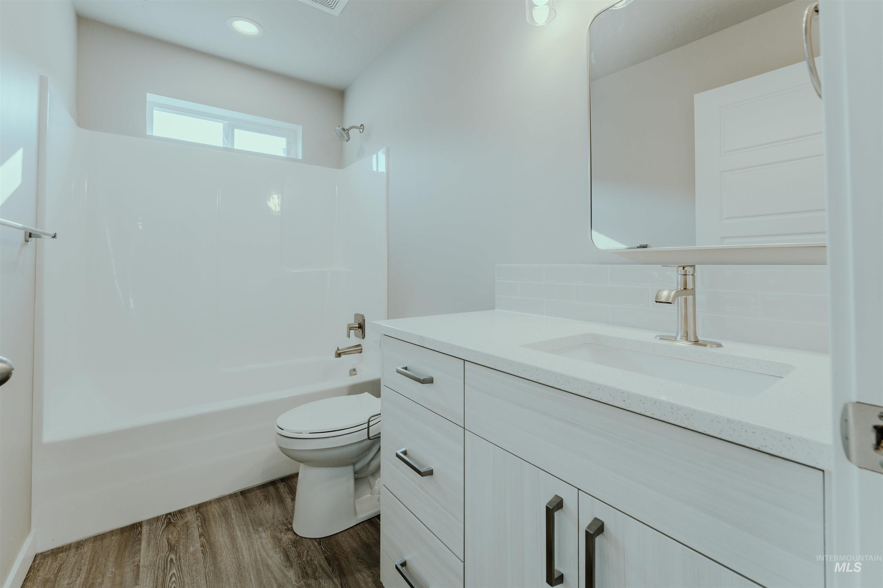 Full bathroom with tub / shower combination, vanity, and dark wood finished floors