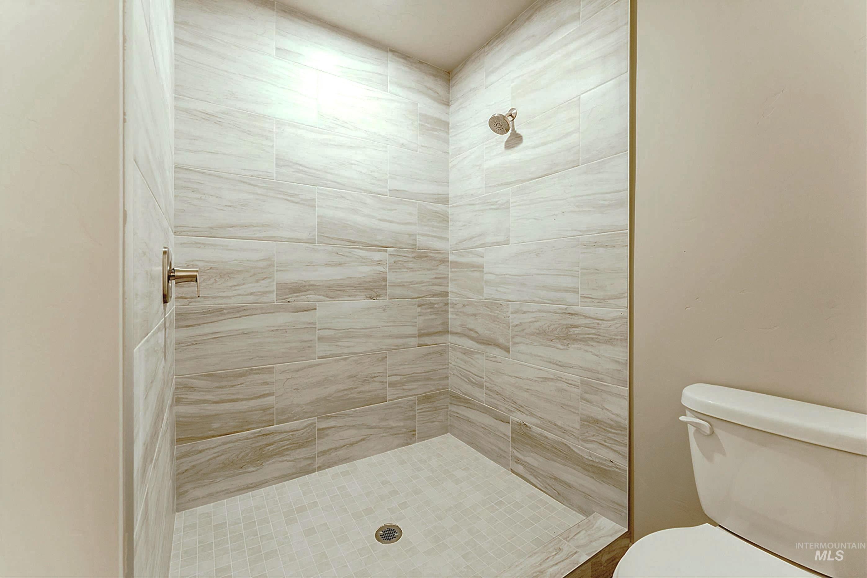 Full bath with a tile shower and toilet