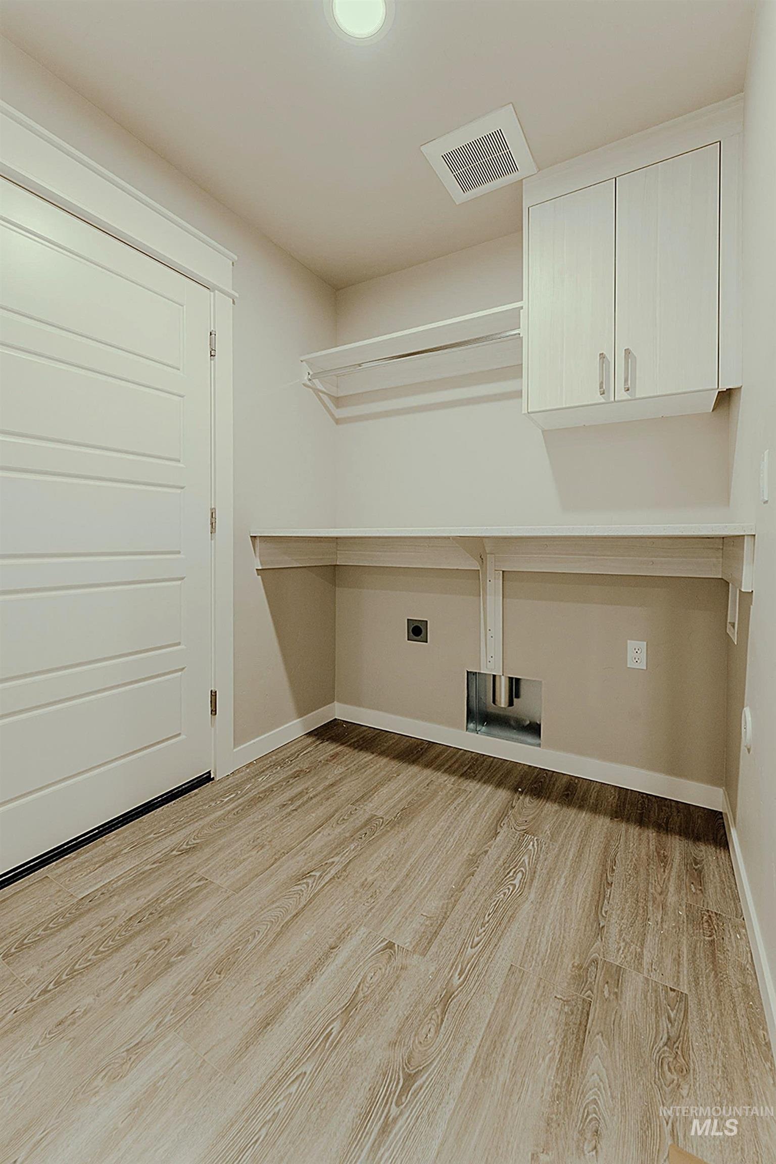 Washroom with light wood-style flooring, hookup for an electric dryer, cabinet space, and washer hookup