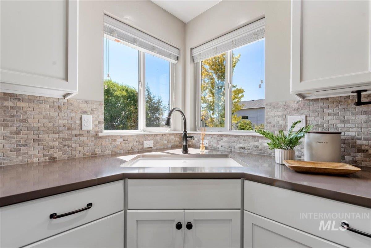 Kitchen featuring white cabinets, dark countertops, and tasteful backsplash