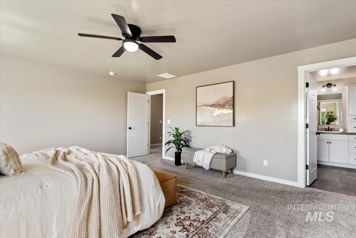 Bedroom with a ceiling fan, connected bathroom, and carpet flooring