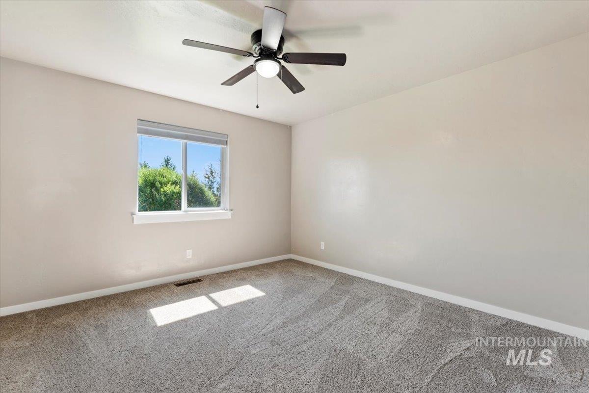 Carpeted spare room with baseboards and ceiling fan