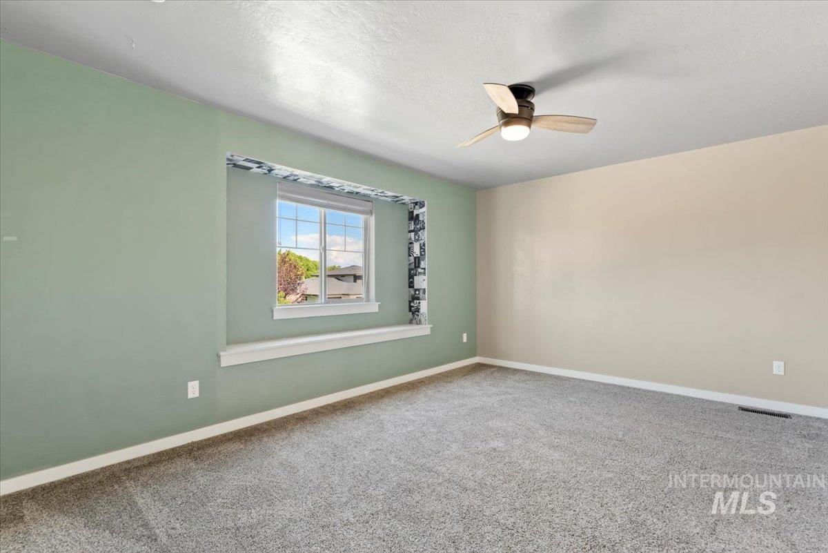Carpeted spare room with a ceiling fan and a textured ceiling