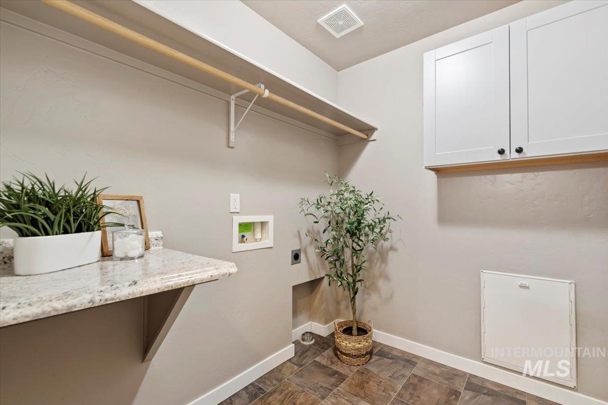 Washroom with cabinet space, washer hookup, electric dryer hookup, and dark stone finish flooring