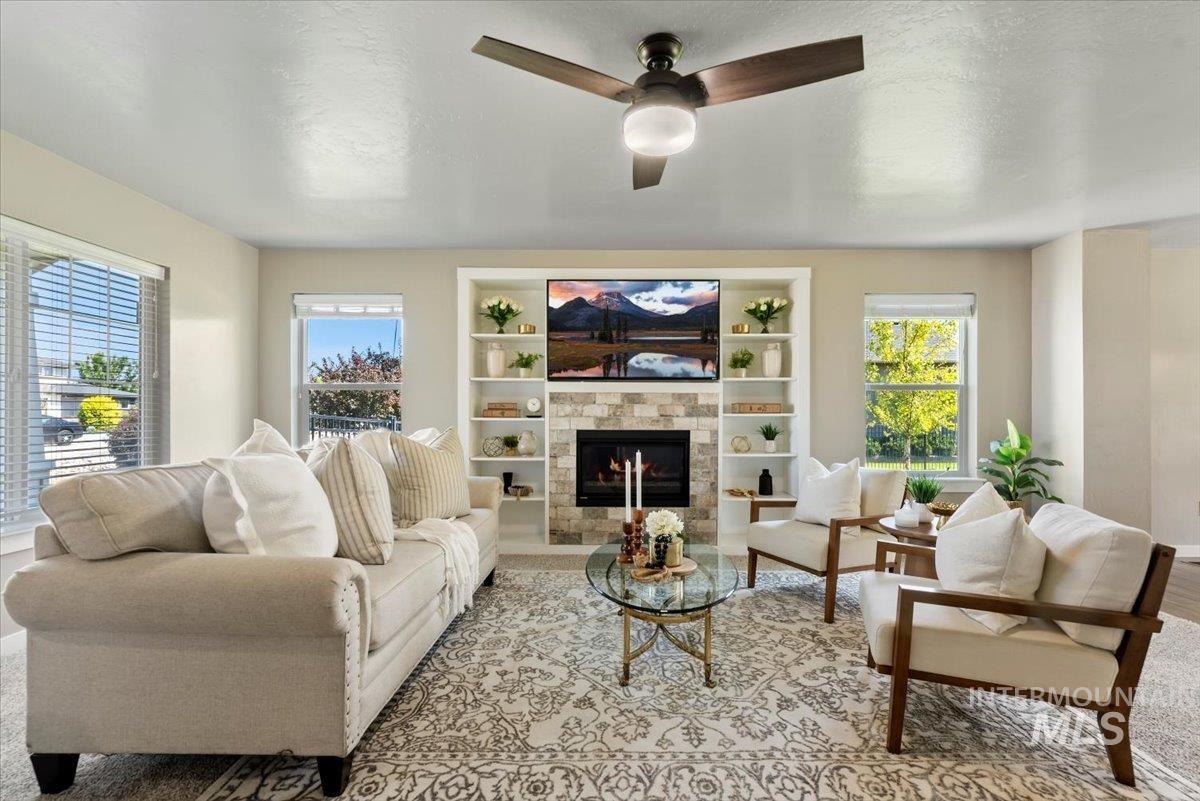 Living room with a tile fireplace, ceiling fan, and a textured ceiling